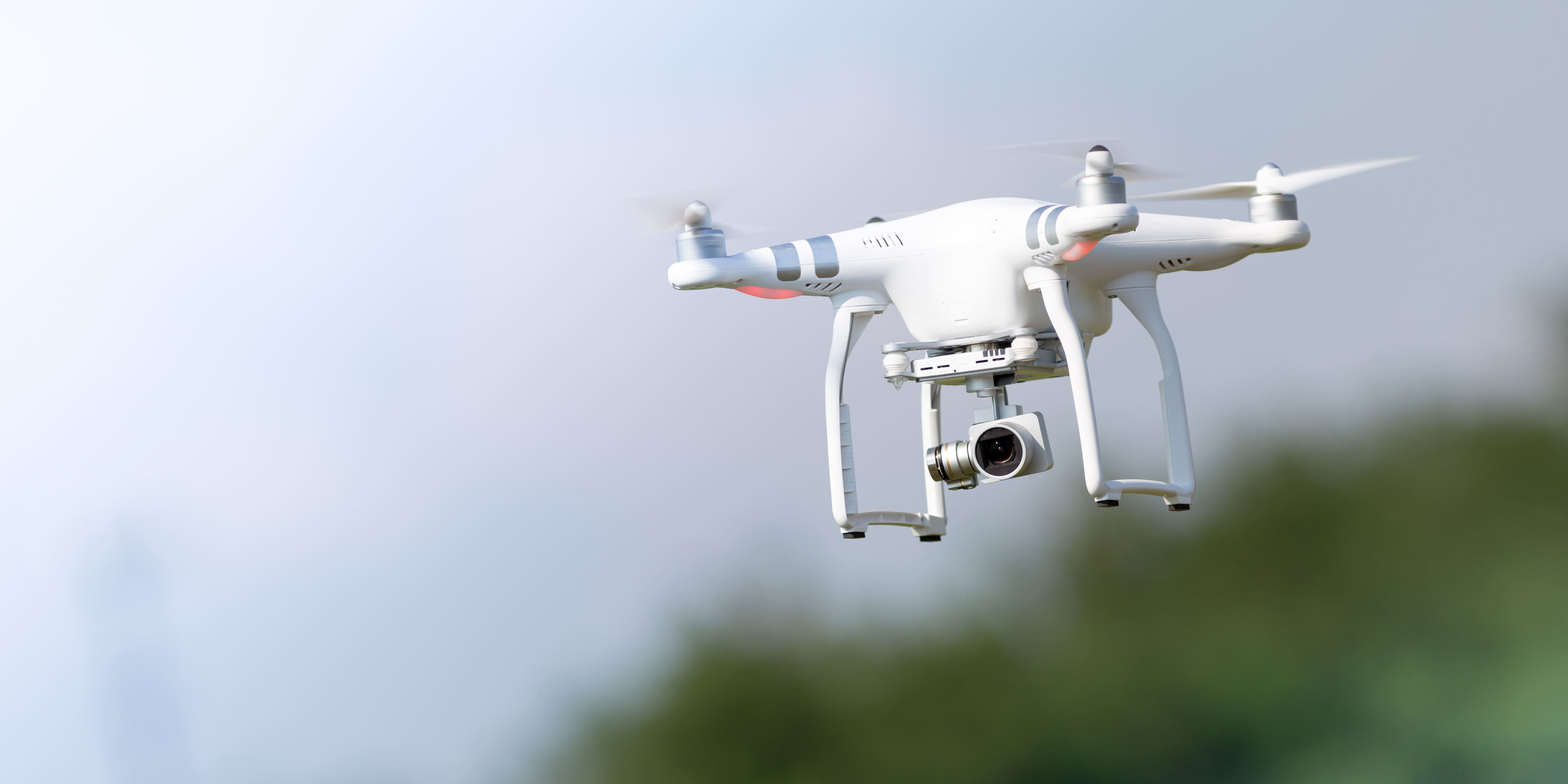 Drone flying in the sky above trees.